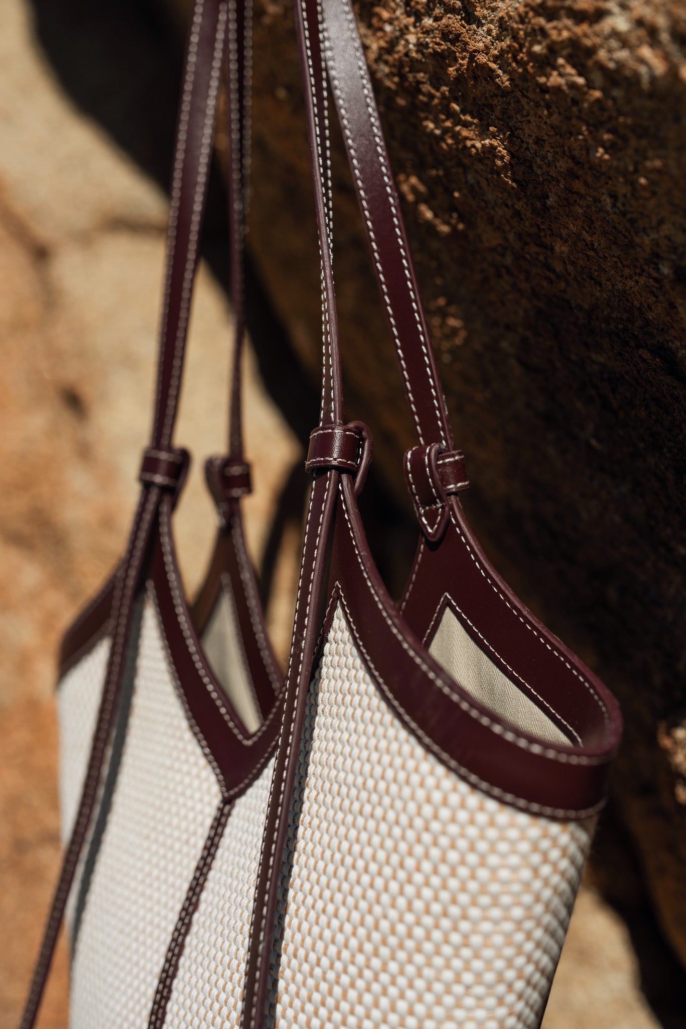 Handbag with woven pattern and burgundy accents on a textured background