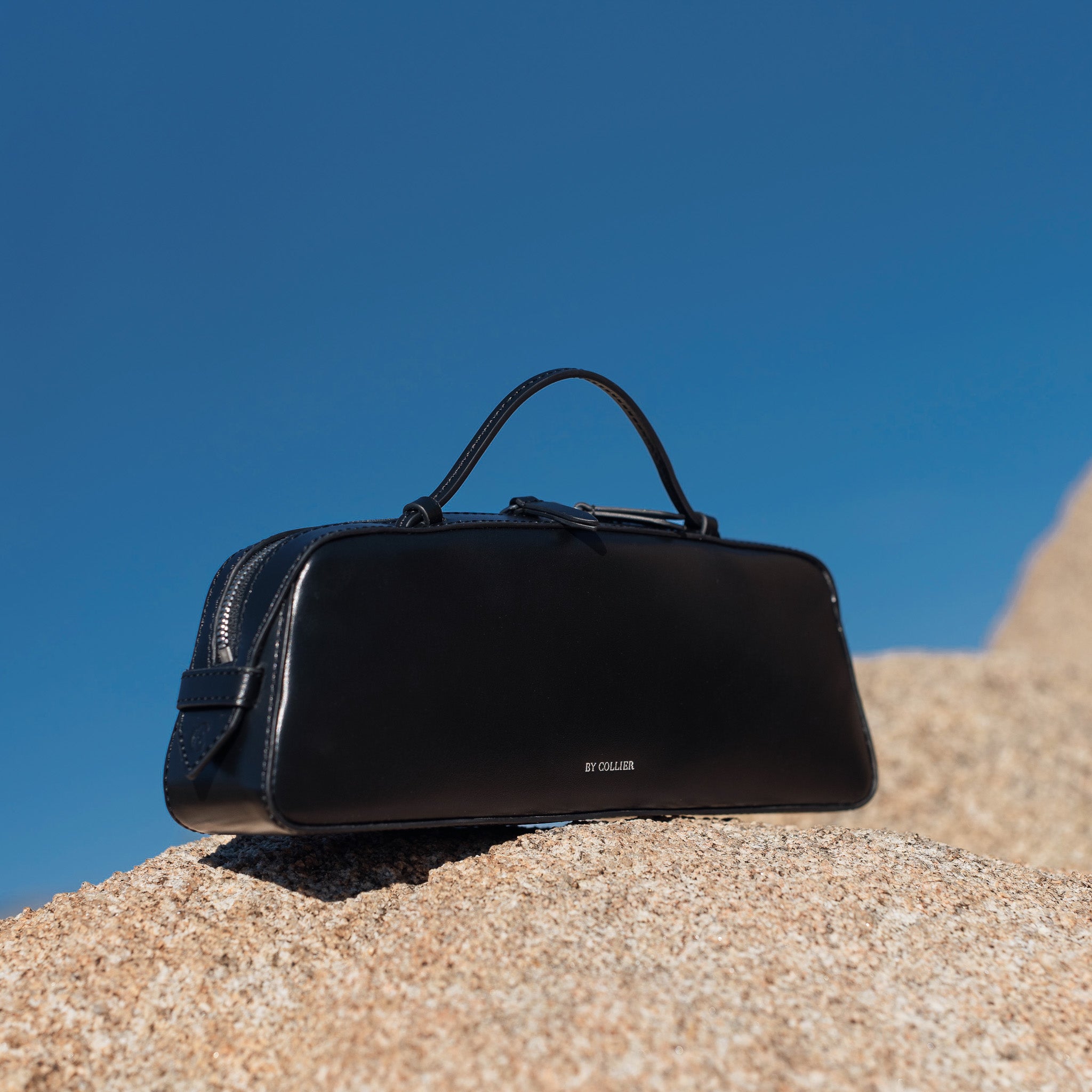 Black bag on a rock with a clear blue sky background