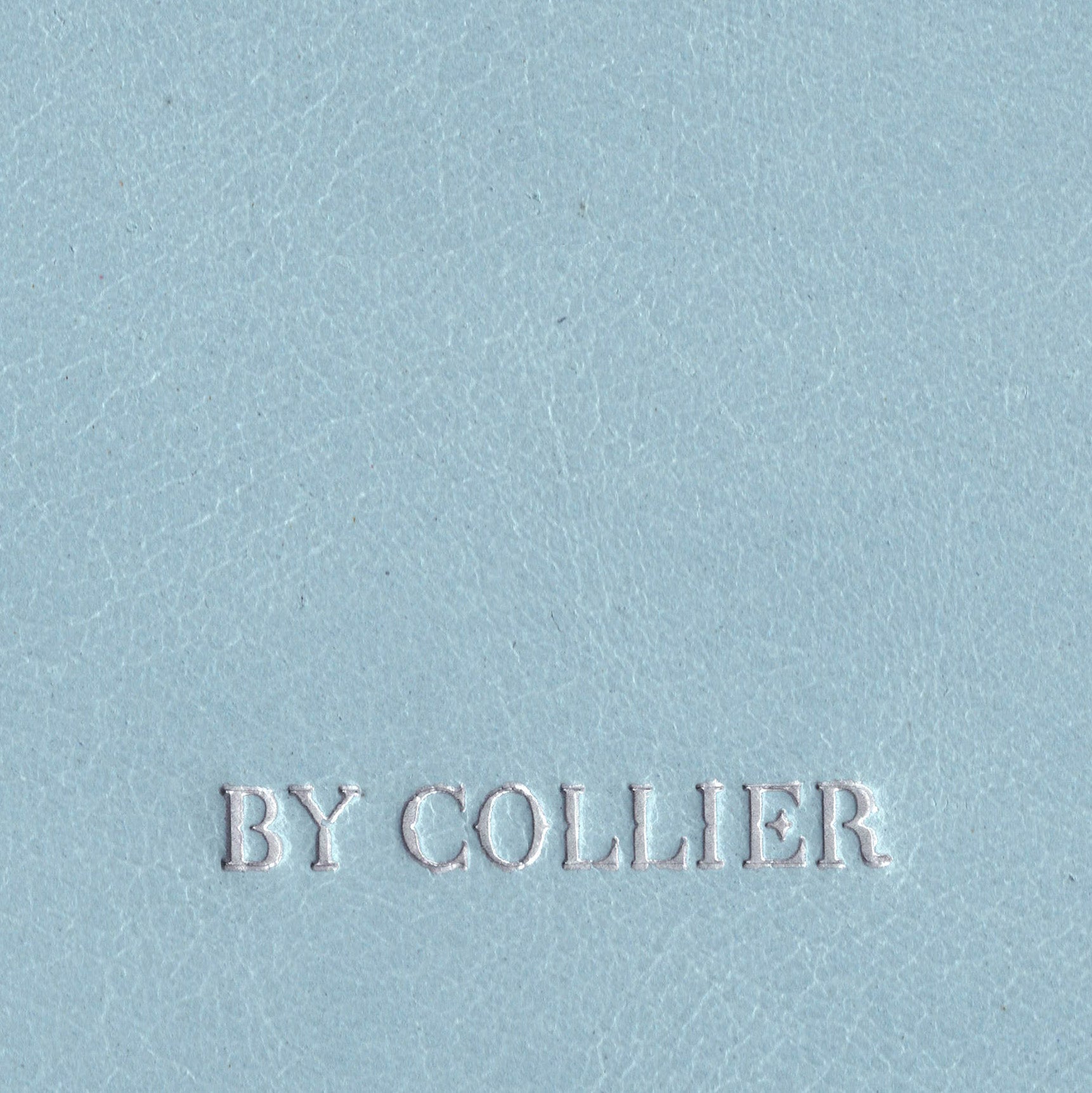 Light blue leather surface with 'BY COLLIER' embossed in white.